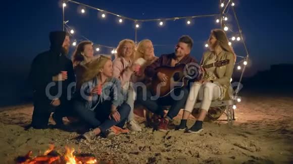沙滩音乐一群年轻人在沙滩上的晚上篝火中尽情娱乐视频的预览图