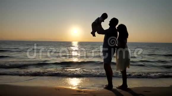 父母和婴儿的剪影父亲的孩子海上日出视频的预览图