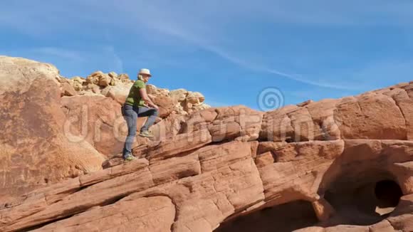 从侧面看一个女人爬上红岩天空视频的预览图