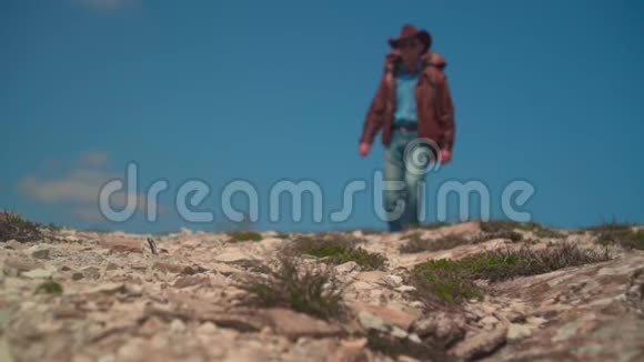 在山上一个男人戴着牛仔帽皮夹克蓝色牛仔裤背着一个大型旅游背包视频的预览图