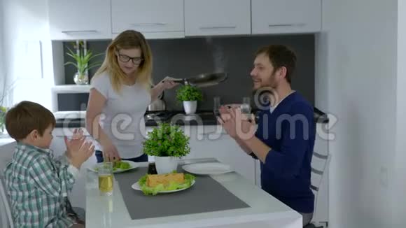 刚准备好的食物女人正在厨房的餐桌上喂男人和孩子视频的预览图