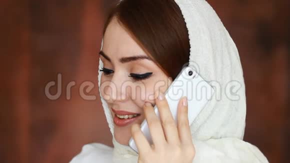一位戴着传统头巾的漂亮阿拉伯女人的肖像特写在手机上交流穆斯林视频的预览图