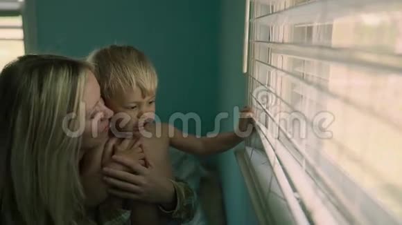 特写肖像美丽的母亲抱着一个小儿子大窗户在背景中视频的预览图