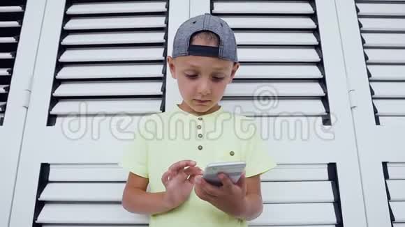 一个满意的可爱的小男孩在智能手机上玩游戏的肖像隔离在白色背景上儿童在线游戏视频的预览图