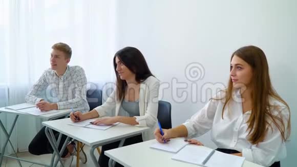 年轻人坐在桌子旁在教室里做学校作业视频的预览图