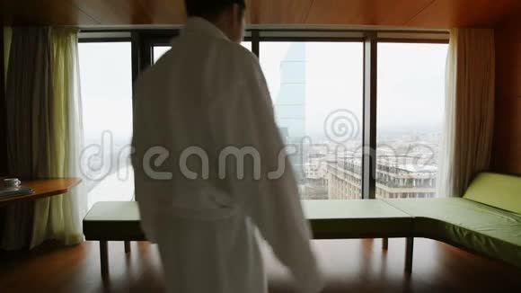 年轻人在豪华公寓酒店醒来成功的男性穿着浴袍在早晨伸展身体视频的预览图
