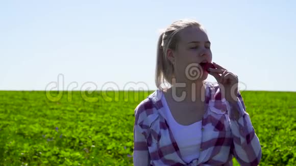年轻漂亮的女孩在绿色种植园的背景下享受新鲜甜草莓视频的预览图