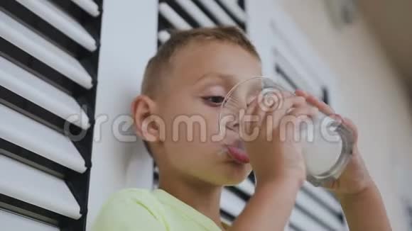 微笑男孩的肖像是在阳光明媚的日子在户外喝牛奶奶胡子可爱的白种人儿童饮用来自视频的预览图