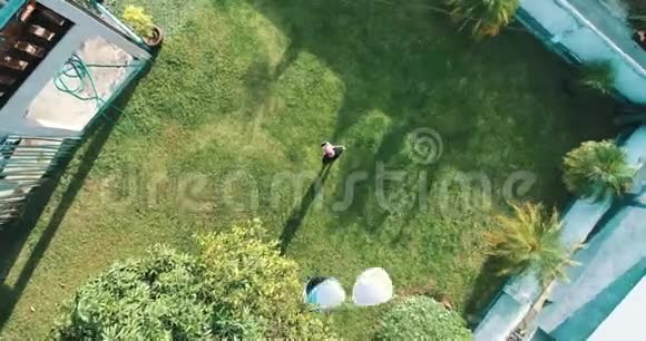 无人机操作员站在草地上遥控无人机面上戴太阳镜时的鸟瞰图视频的预览图