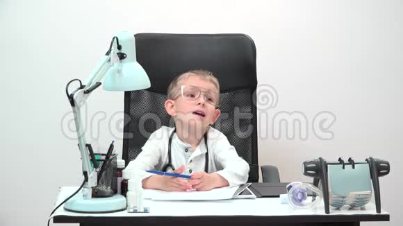 有趣的带大眼镜和听诊器的儿童医生坐在他的办公室里真正的专业医生视频的预览图