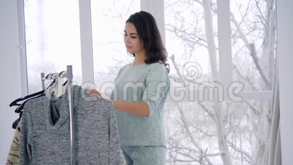 年轻女性在橱窗的背景下从衣柜里试穿衣服视频的预览图