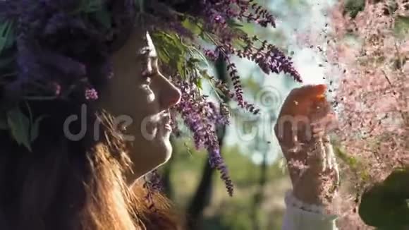 特写镜头美丽的女人头上戴着矢车菊看上去在树林中粉红的灌木丛中绽放视频的预览图