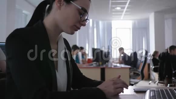 不感兴趣的工作沮丧迷人的戴着眼镜的女孩看着自己坐在桌子旁视频的预览图