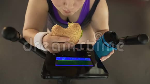 胖女孩一边吃汉堡一边喝水一边骑自行车视频的预览图