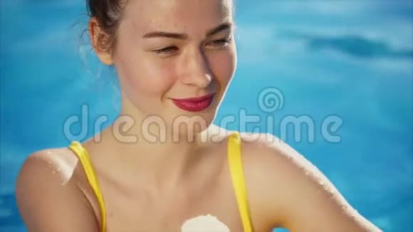 一个年轻苗条的女人用喇叭吃冰淇淋在游泳池里休息视频的预览图
