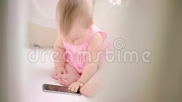 婴儿床上坐着移动的女孩宝宝看小孩卡通片视频的预览图