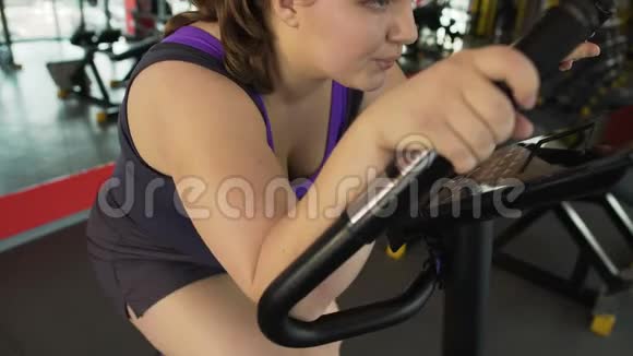 精疲力竭的肥胖女性坐在静止的自行车上呼吸困难视频的预览图