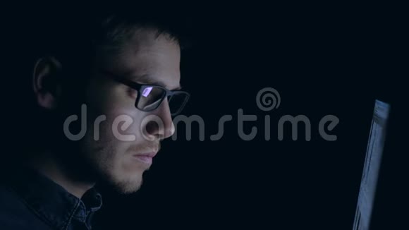戴眼镜的人晚上在笔记本电脑上工作视频的预览图