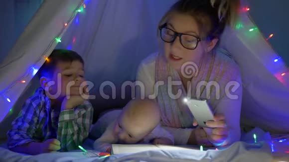 该睡觉了妈妈拿着一部手电筒在wigwam为儿子读书视频的预览图