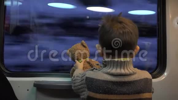 小孩子拿着玩具熊玩具看着窗外在生活中纳闷冬天的风景视频的预览图