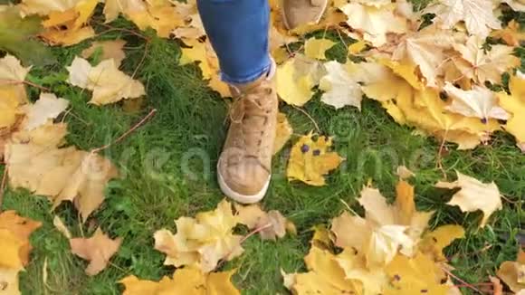 穿靴子的女人的腿紧贴着身子穿过绿绿的草坪黄秋叶视频的预览图