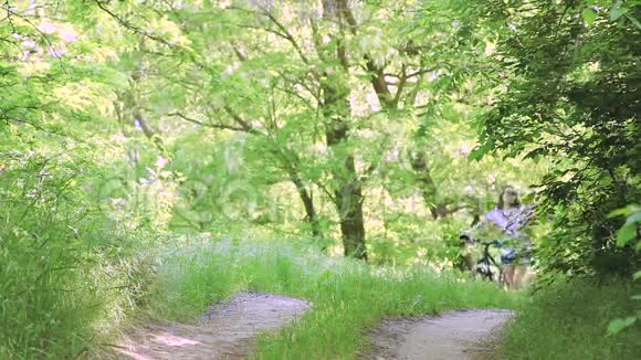 一对漂亮的年轻夫妇在夏天骑着自行车在公园里散步时说得很活泼视频的预览图