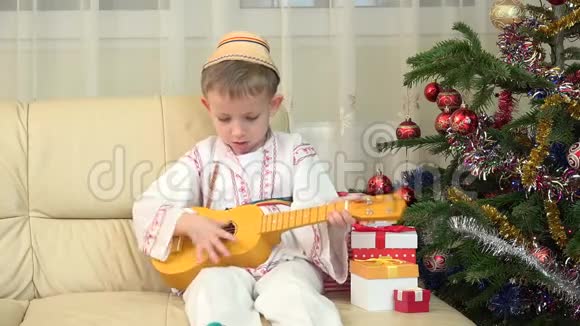 可爱的孩子在吉他旁演奏圣诞树传统套装视频的预览图