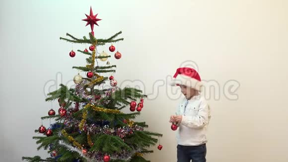 可爱的孩子圣诞老人的帽子装饰圣诞树视频的预览图