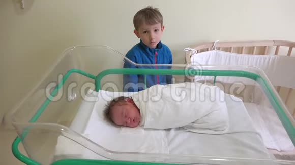 大哥看着他刚出生的弟弟婴儿睡在医院的床上视频的预览图