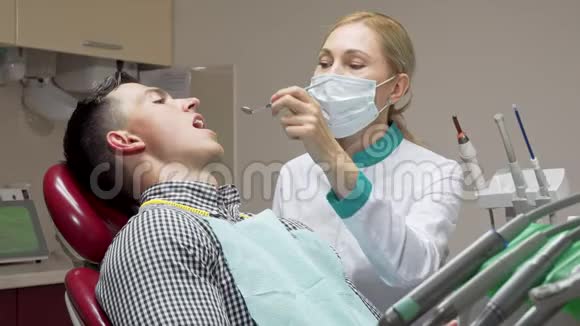 女牙医检查她的病人的牙齿在牙科诊所工作视频的预览图