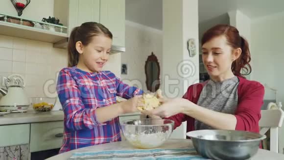 快乐的母亲和美丽的女儿一起做饭玩得很开心妈妈从女孩手里取出黏糊糊的面团视频的预览图