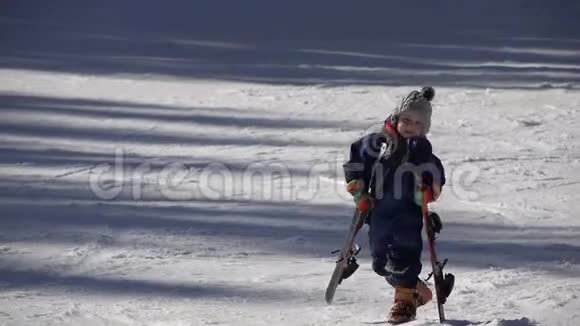 幼儿携带重型滑雪器材热爱冬季运动视频的预览图