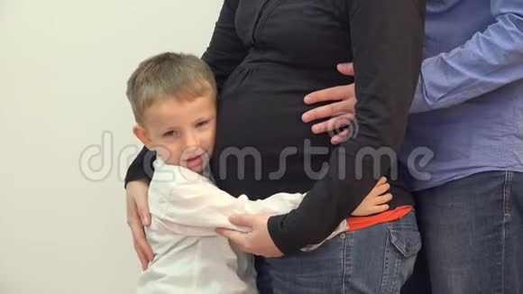 快乐的孩子和爸爸手拥抱怀孕的妈妈肚子细节视频的预览图