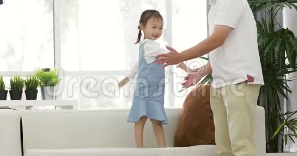快乐的亚洲父亲和小女儿玩得开心把小女孩扔了出来在客厅里视频的预览图
