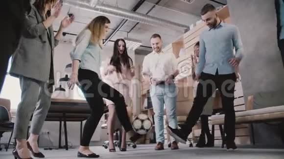 年轻的办公室员工在休息时踢足球休闲员工享受健康的职场氛围慢动作视频的预览图