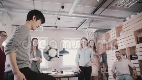 亚洲男人休息时在办公室踢足球快乐的朋友站在圈里举行体育活动慢动作视频的预览图