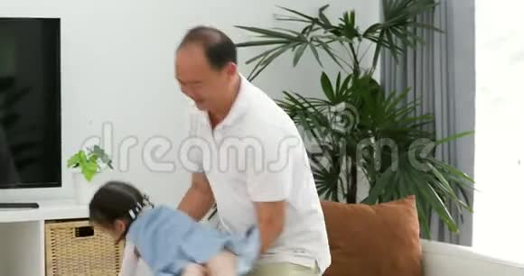 快乐的亚洲父亲和小女儿玩得开心把小女孩扔了出来在客厅里视频的预览图