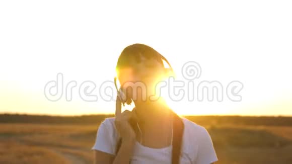 戴着耳机的年轻女孩走在路上听音乐跳舞视频的预览图