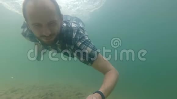 自由职业者在水下慢动作潜水时使用智能手机天然湖泊视频的预览图