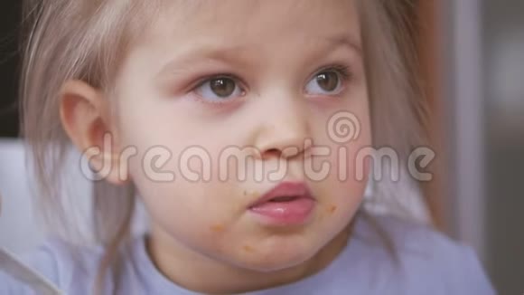 一个小女孩吃了一勺蔬菜汤弄脏了脸仔细地看电视视频的预览图