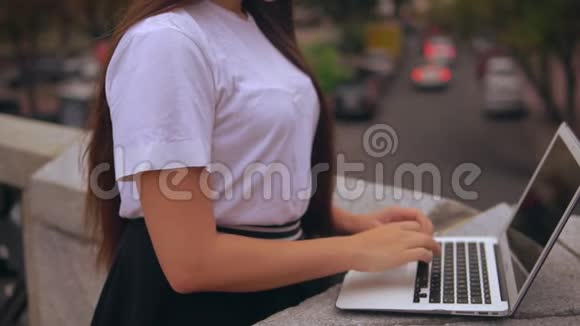 无法辨认的女孩在户外电脑上工作视频的预览图