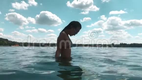 穿条纹泳衣在海中摆姿势的迷人年轻女士视频的预览图