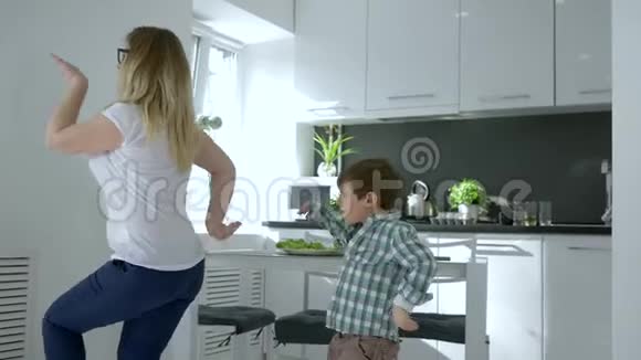 家庭聚会妈妈带着孩子在厨房的公寓里欢快地跳舞视频的预览图