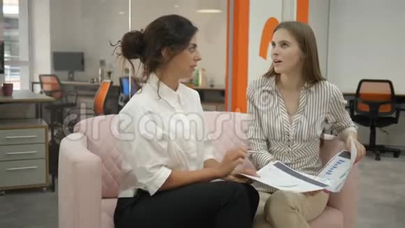 两个女人坐在办公室的沙发上谈论着工作日程情绪化地交流着视频的预览图