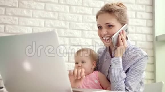微笑的女人带着孩子说电话快乐的商业母亲在家工作视频的预览图