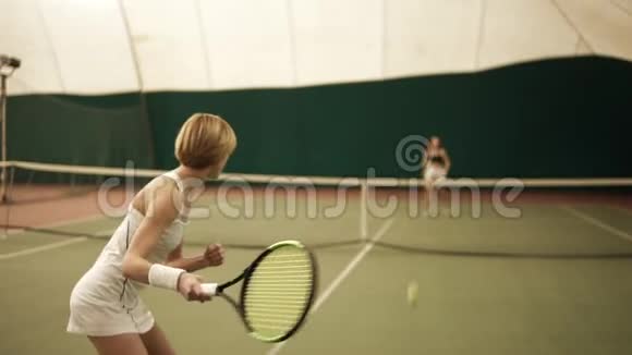 肌肉发达的金发女运动员与一个无法辨认的女性在后台打网球慢镜头已覆盖视频的预览图