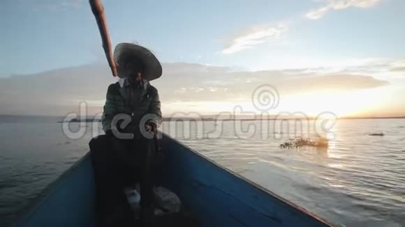 非洲渔民黎明时坐在船上戴草帽的年轻人早上出海视频的预览图