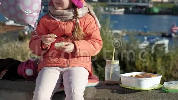小女孩戴着粉红色的帽子带着气球在河港晚餐特写视频的预览图