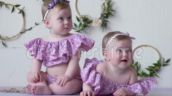 两个穿着粉色服装的女孩在墙的背景上摆着装饰的照片视频的预览图