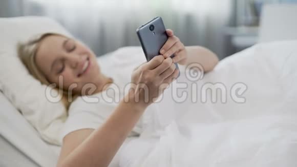 快乐的少女刚刚醒来用智能手机上网视频的预览图